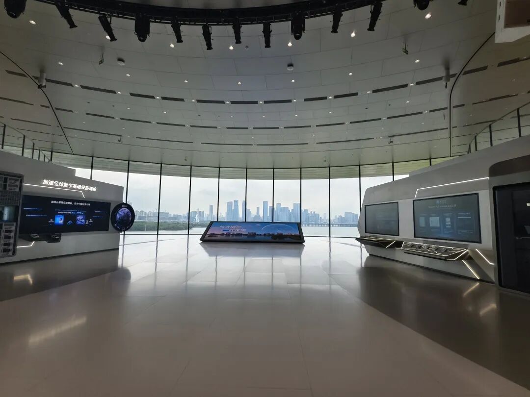 Interior of the exhibition hall at Tencent headquarters in Shenzhen with the city skyline visible through the curved windows