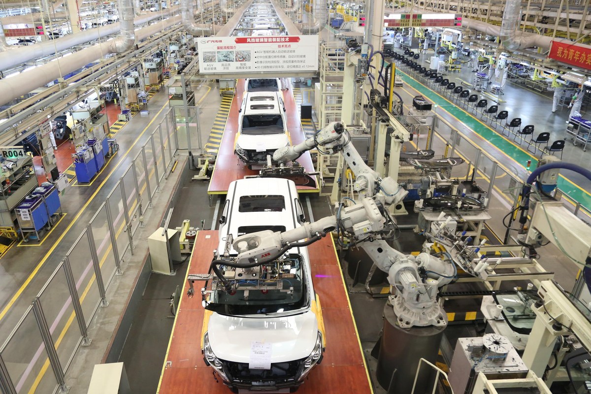 Overhead view of the GAC Trumpchi final-assembly line with robotic door-fitting arms