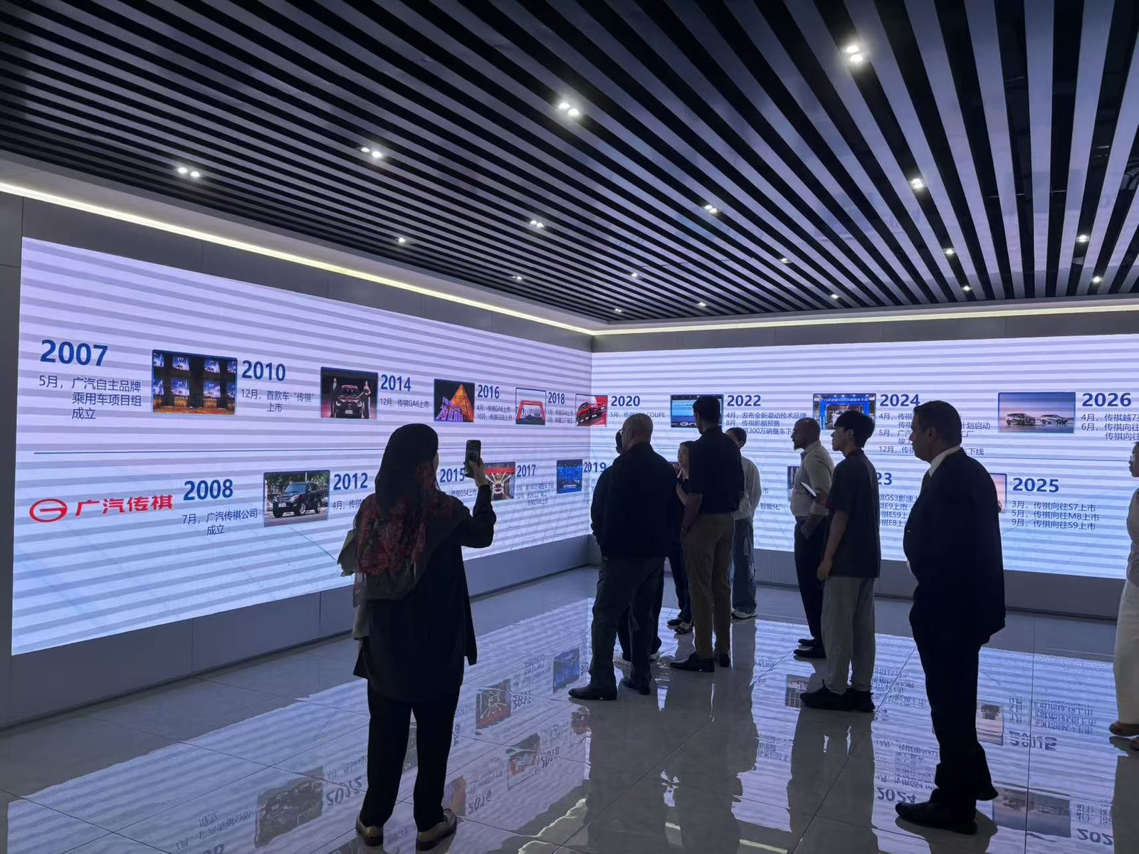 Visiting delegation reviewing the GAC Trumpchi brand timeline wall in Guangzhou