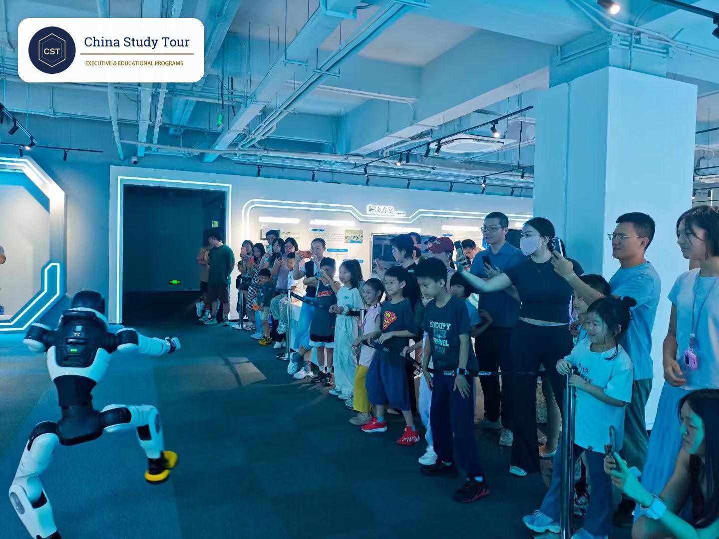 Children watch a humanoid robot demonstration from behind a rope line in a robotics showroom